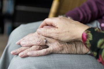 Hands of two senior citizens rest on each other.